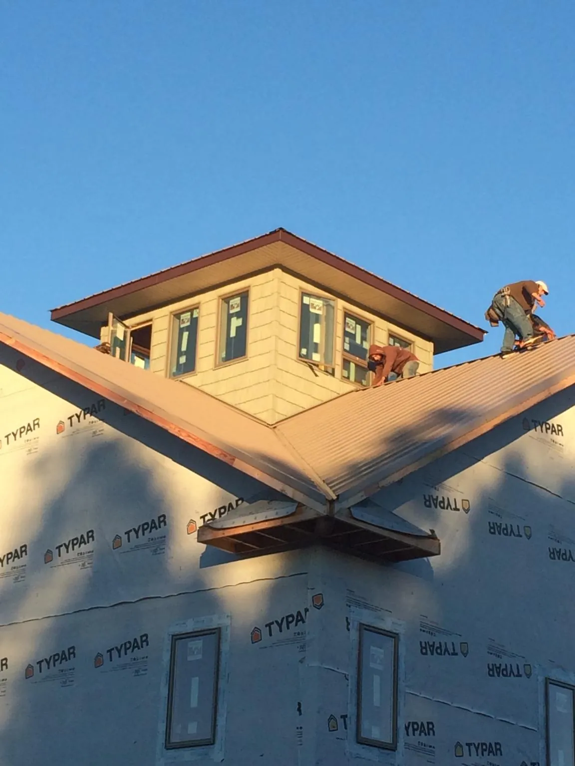 Roofers working around a rooftop cupola on a new metal roof at sunset — Roof Waterproofing in Pharr by Roofing Brothers